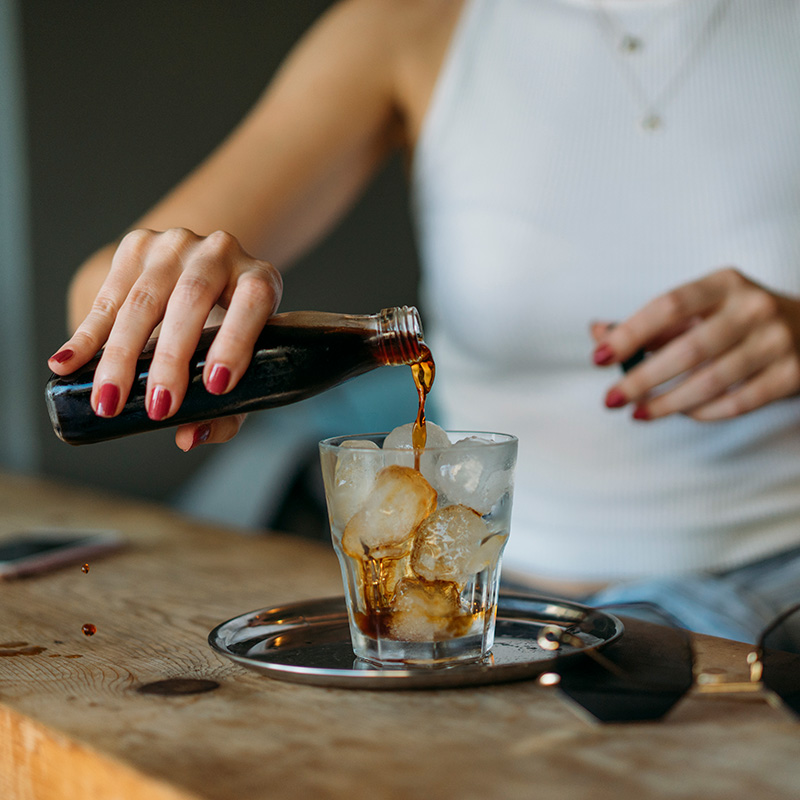 woman pouring cold brew coffee into an iced glass woman pouring cold brew coffee into an iced glass